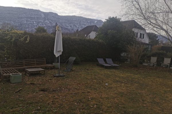 Espace extérieur avec mobilier de jardin et pelouse en hiver, en attente d’aménagement paysager, avec vue sur les montagnes enneigées en Suisse